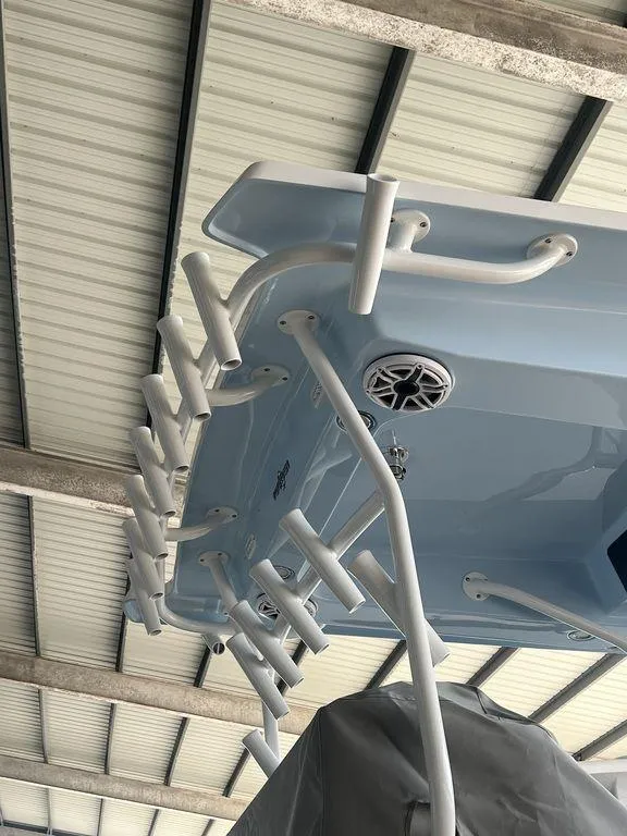 Slide: The Image of 2024 Fountain 34 TE boat under a metal roof, showcasing rod holders and speaker. - 18