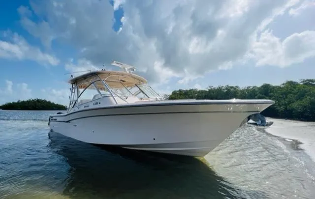 Slide: The Image of 2014 Grady-White Freedom 335 boat anchored near a scenic shoreline under a partly cloudy sky. - 2