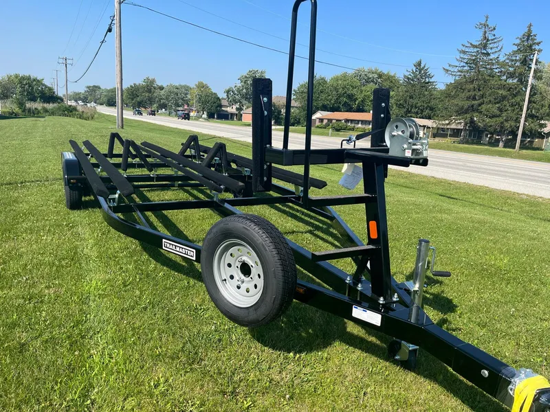 Slide: The Image of 2024 Pontoon Trailer on grass, side view, black frame, single axle, winch system. - 2