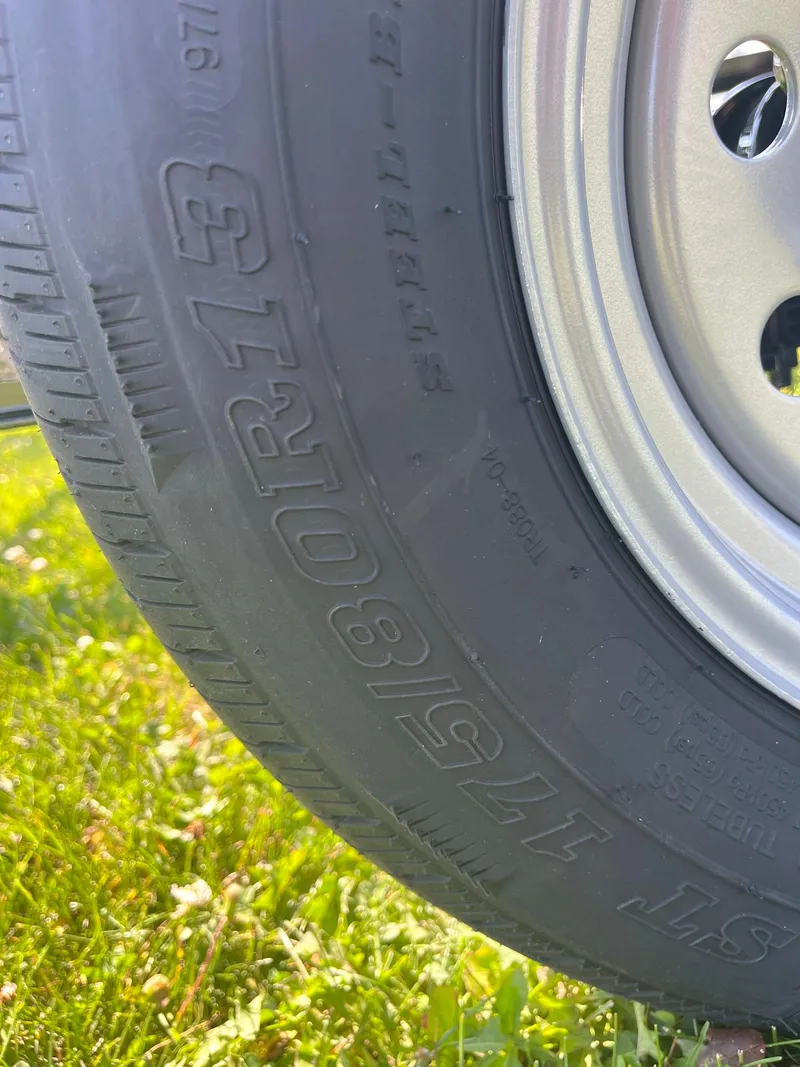 Slide: The Image of Close-up of a 2024 Pontoon Trailer tire on grass. - 5