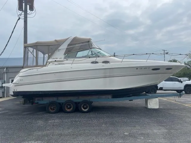 The Image of 1999 Sea Ray 310 DA boat on a trailer in a parking lot. - 0