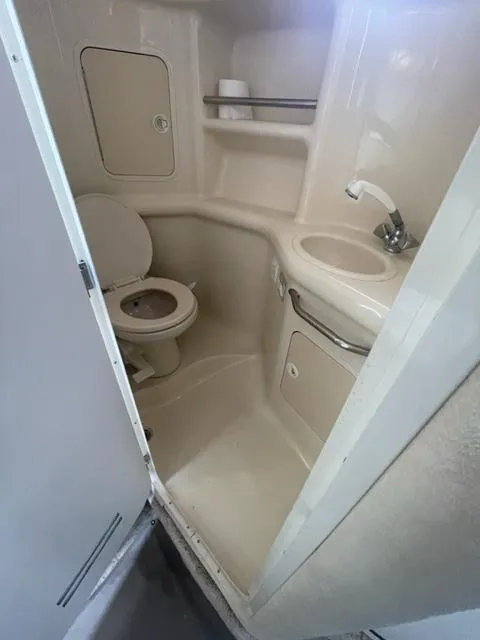Slide: The Image of Compact bathroom in a 1999 Sea Ray 310 DA boat with toilet, sink, and storage. - 11