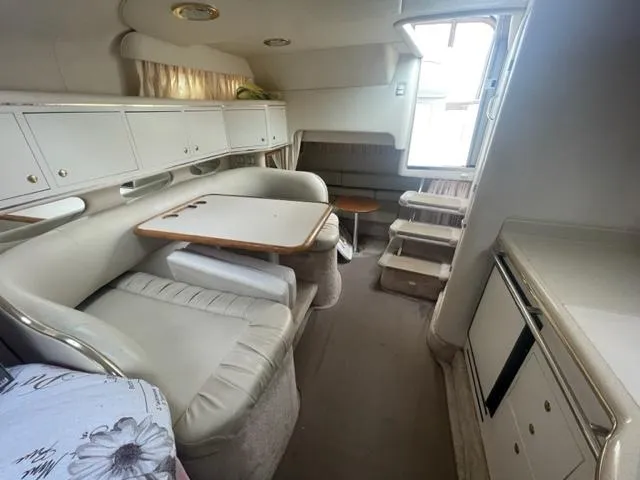 Slide: The Image of 1999 Sea Ray 310 DA cabin interior with dining area, kitchenette, and stairs to deck. - 13