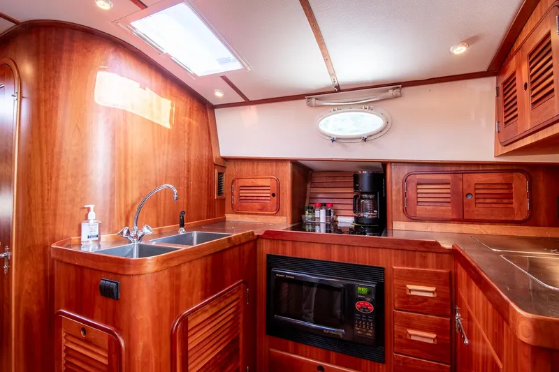 Slide: The Image of 2003 Hinckley Talaria 44 Express yacht kitchen with wood cabinetry, sink, and microwave. - 32