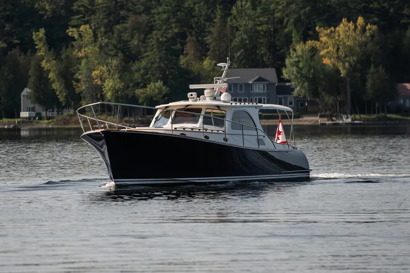 Slide: The Image of 2003 Hinckley Talaria 44 Express cruising on a serene lake with forested shoreline. - 43