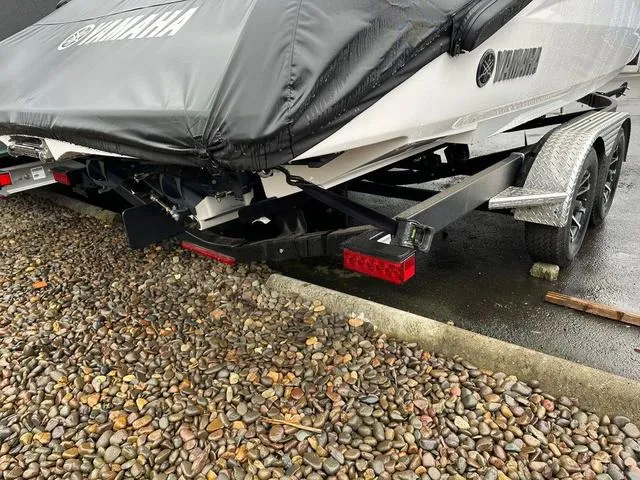 Slide: The Image of 2024 Yamaha Boats 255XE on trailer, covered, parked on gravel. - 16