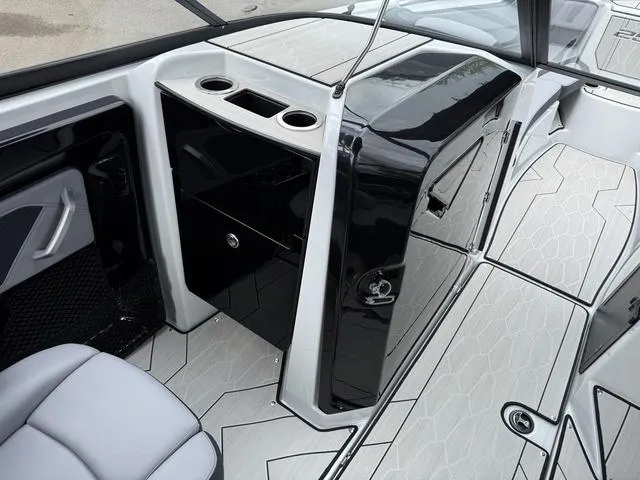 Slide: The Image of 2024 Yamaha Boats 255XE interior with sleek black and white design, featuring storage and cup holders. - 7