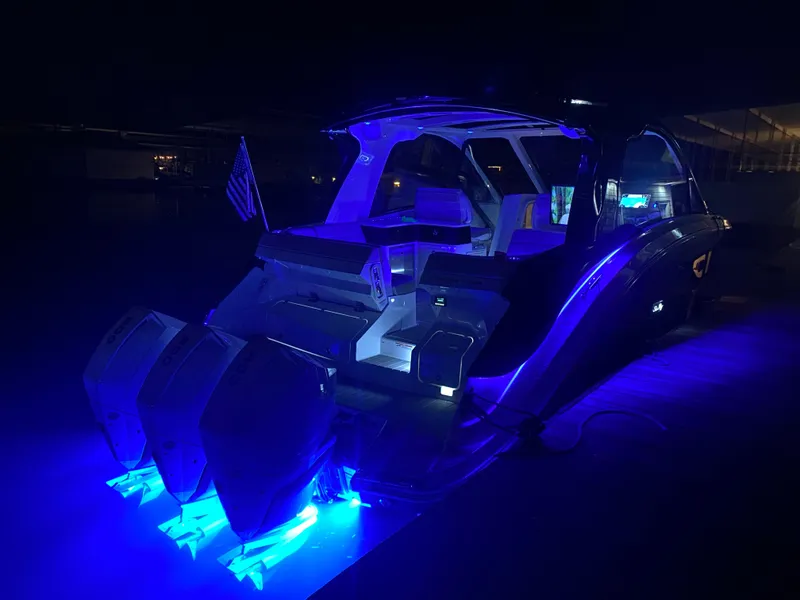 Slide: The Image of 2025 Sea Ray Sundancer 370 OB docked at night with blue LED lights. - 22