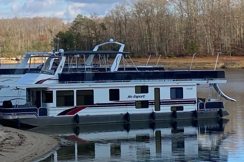 Slide: The Image of 2006 Sumerset Houseboat docked on a calm lake with a forested background. - 0