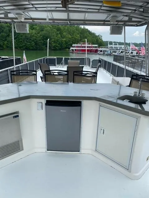 Slide: The Image of 2006 Sumerset Houseboat with outdoor seating and kitchenette on a lake. - 24