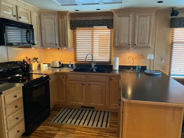 Slide: The Image of Modern kitchen in a 2006 Sumerset Houseboat with wooden cabinets and black appliances. - 8