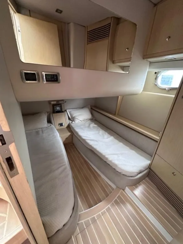 Slide: The Image of 2006 Baia 63 Azzurra yacht cabin with twin beds and wooden interior. - 8