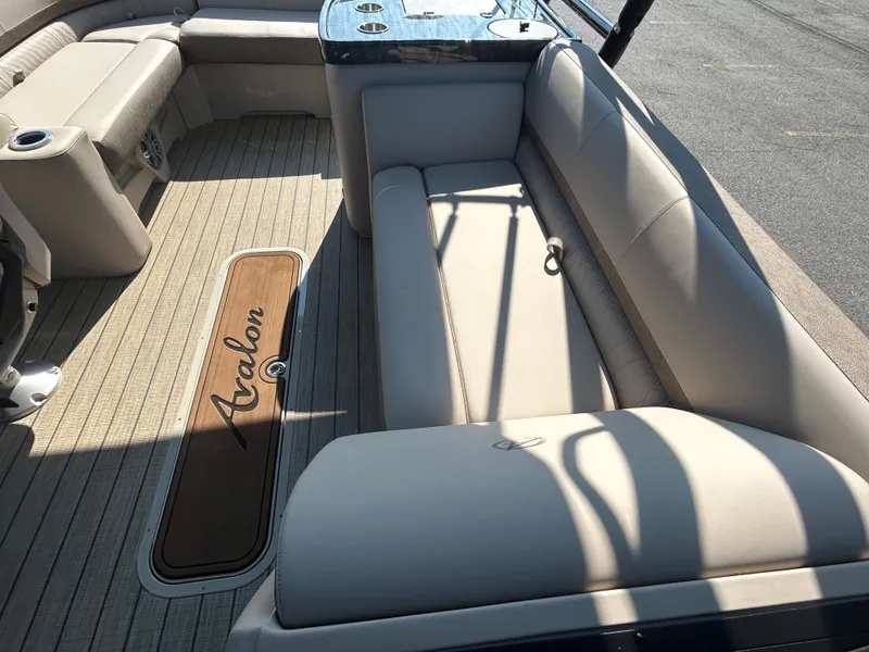 Slide: The Image of 2024 Avalon LSZ 2385 EL boat interior with beige seating and Avalon logo on floor. - 20