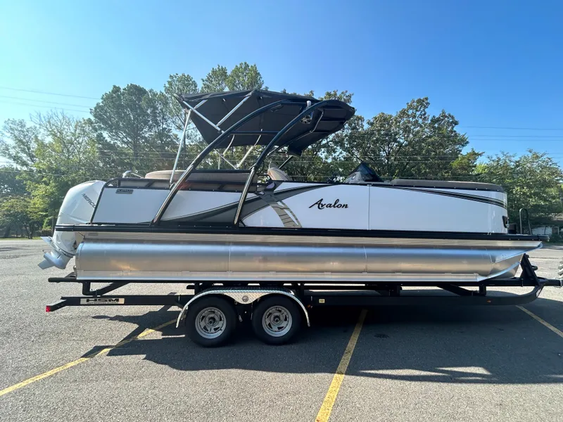 Slide: The Image of 2024 Avalon LSZ 2385 EL pontoon boat on a trailer in a parking lot. - 5