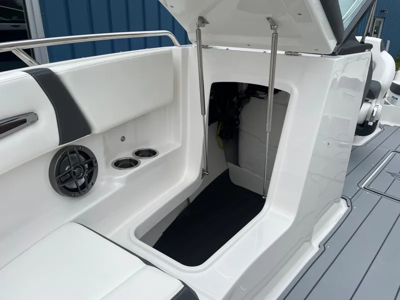 Slide: The Image of 2024 Chaparral 247 SSX boat interior storage compartment with cup holders and speaker. - 20