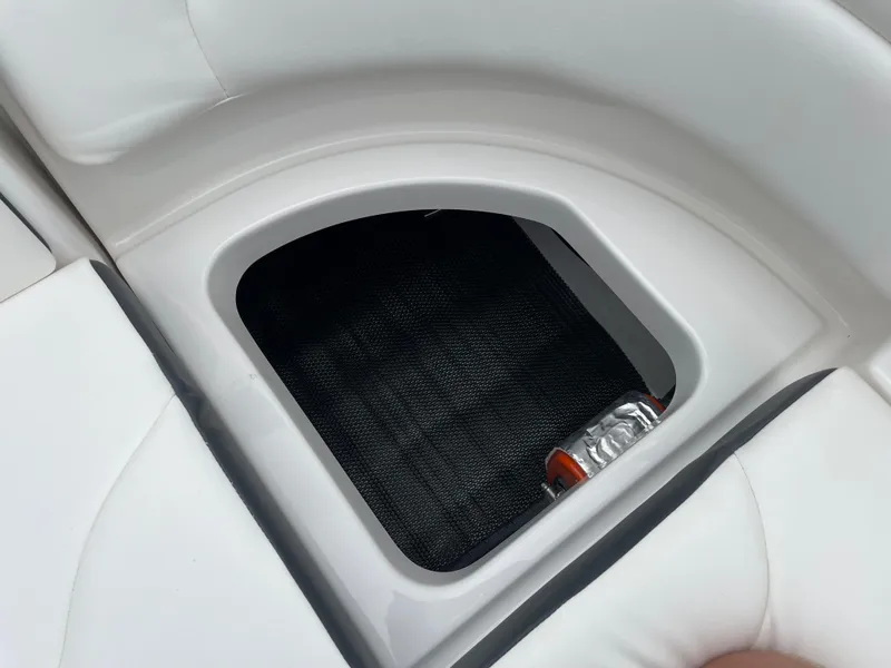 Slide: The Image of 2024 Chaparral 247 SSX boat storage compartment with white cushioned seating. - 29