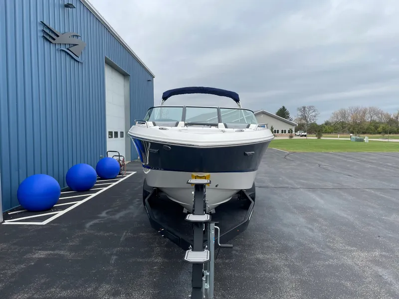 Slide: The Image of 2024 Chaparral 247 SSX boat on trailer outside blue building. - 7