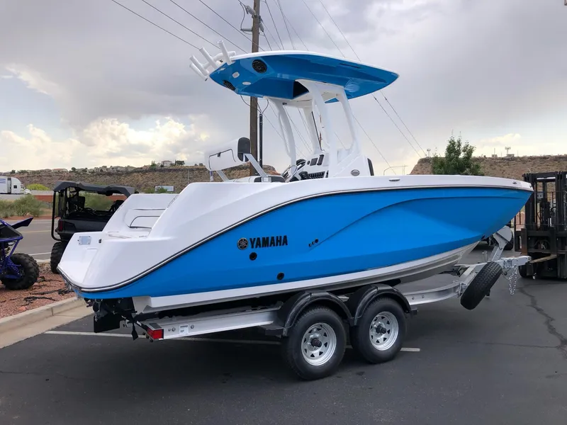 Slide: The Image of 2023 Yamaha Boats 222 FSH Sport E, blue and white, on a trailer. - 3