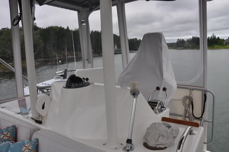 Slide: The Image of 1987 Bertram 37 Convertible boat helm station with covered captain's chair and scenic waterway view. - 22