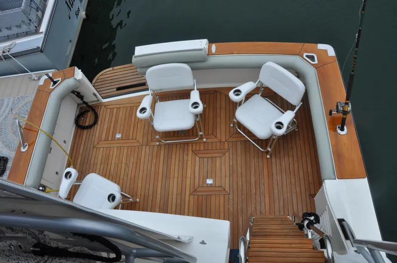 Slide: The Image of 1987 Bertram 37 Convertible boat deck with teak flooring and white chairs. - 28