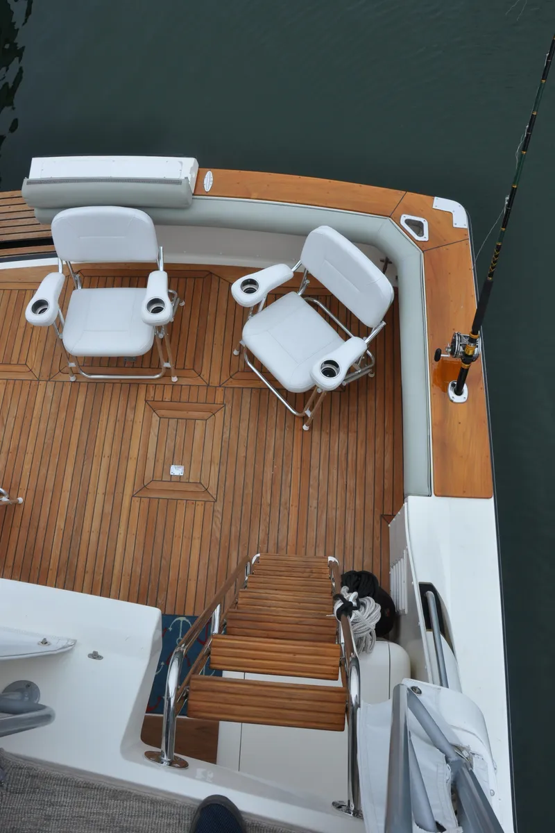 Slide: The Image of 1987 Bertram 37 Convertible boat deck with wooden flooring and white chairs. - 30