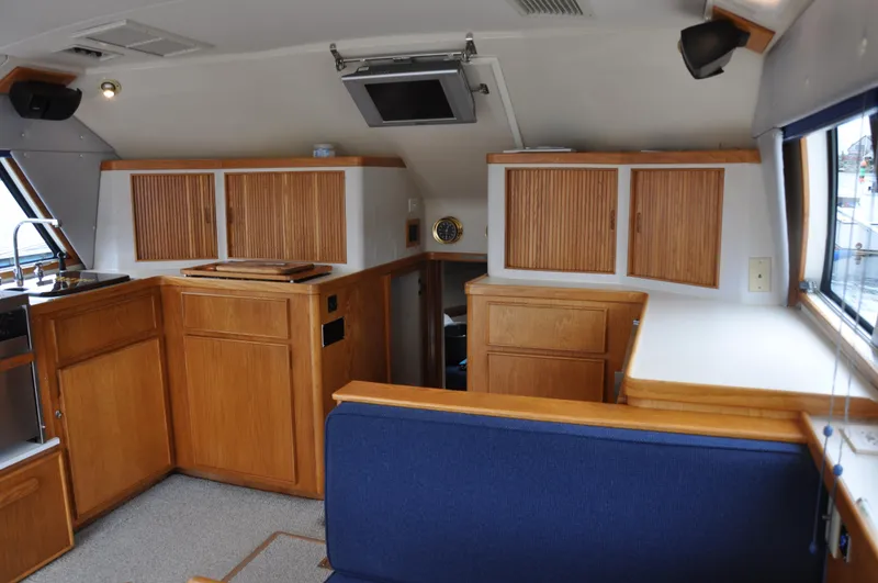 Slide: The Image of Interior of a 1987 Bertram 37 Convertible yacht with wooden cabinetry and blue seating. - 42
