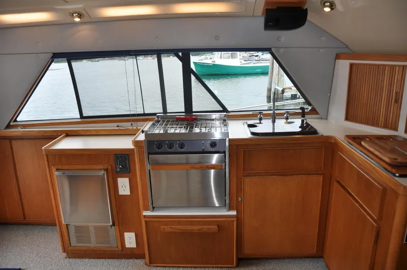 Slide: The Image of 1987 Bertram 37 Convertible yacht kitchen with stove, sink, and wooden cabinets. - 45