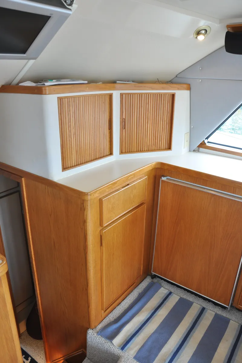 Slide: The Image of Interior of a 1987 Bertram 37 Convertible yacht with wooden cabinetry and striped rug. - 49