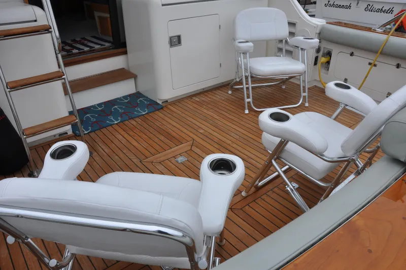 Slide: The Image of 1987 Bertram 37 Convertible boat deck with white chairs and wooden flooring. - 9