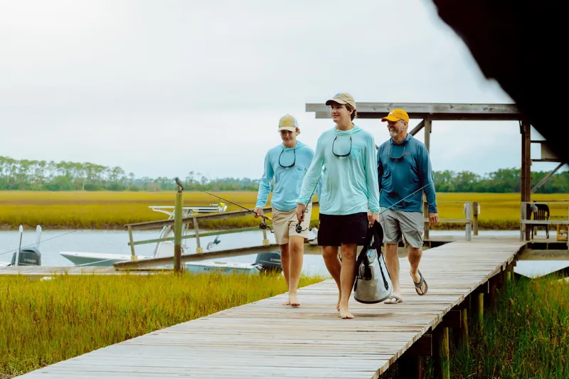 Slide: The Image of Three people walking on a dock near a 2024 Key West 250 Bay Reef boat. - 27