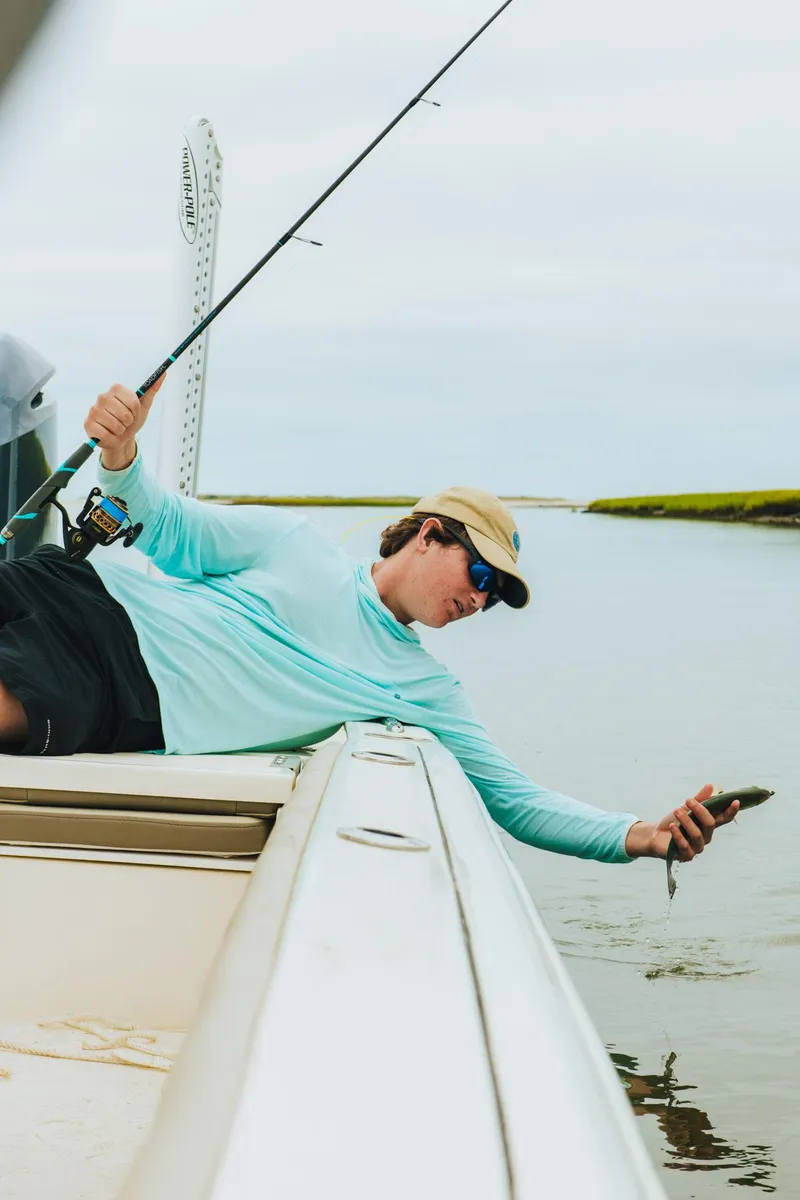 Slide: The Image of Person fishing on a 2026 Key West 250 Bay Reef boat, holding a small fish. - 41