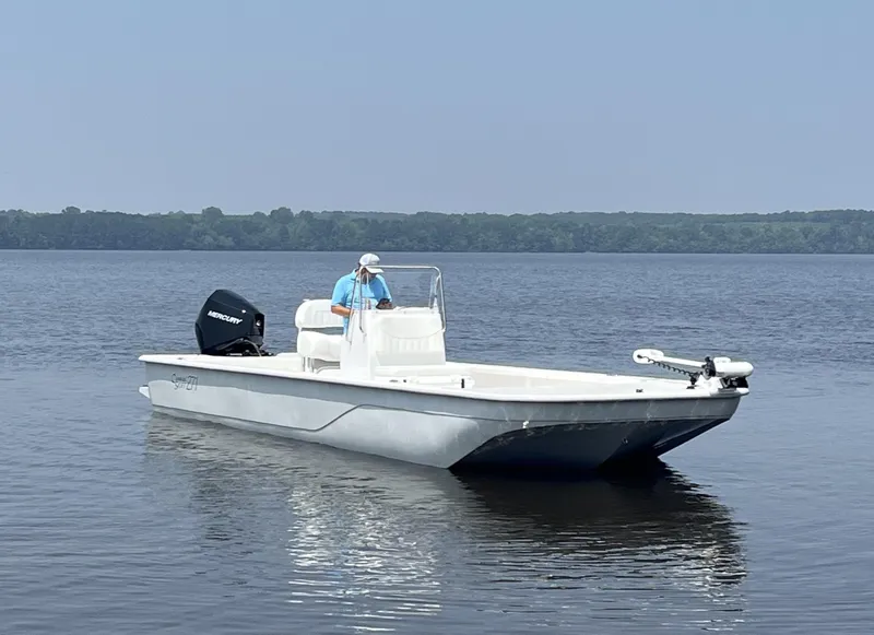 The Image of 2024 Coastal Skiff 271 boat on calm water with a person at the helm. - 1
