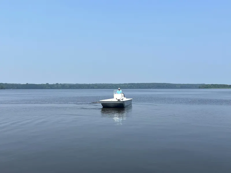 Slide: The Image of 2024 Coastal Skiff 271 on calm lake waters under clear blue sky. - 10