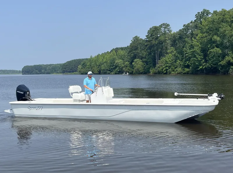 Slide: The Image of 2024 Coastal Skiff 271 boat on a calm lake with a person onboard. - 11