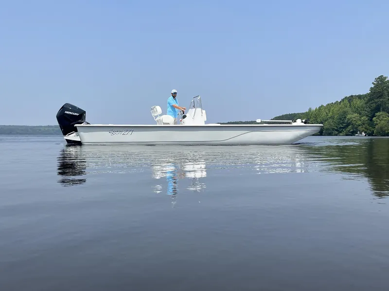 Slide: The Image of 2024 Coastal Skiff 271 boat on calm water with a person onboard. - 12