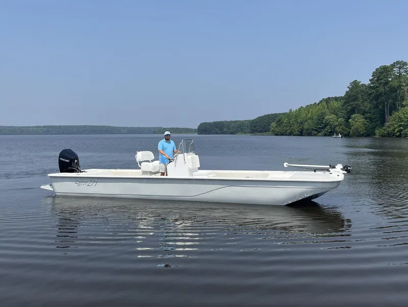 Slide: The Image of 2024 Coastal Skiff 271 boat on calm lake with person at the helm. - 18