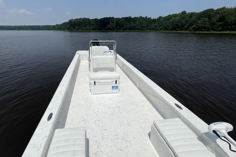 Slide: The Image of 2024 Coastal Skiff 271 on a serene lake with lush green shoreline. - 20