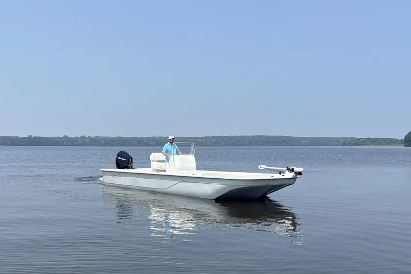 Slide: The Image of 2024 Coastal Skiff 271 boat on calm water with a person at the helm. - 23