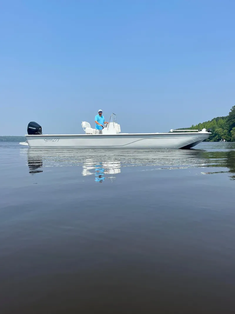 Slide: The Image of 2024 Coastal Skiff 271 boat on calm water with clear blue sky. - 32