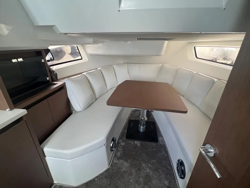 Slide: The Image of 2024 Jeanneau Leader 12.5 cabin interior with white seating and wooden table. - 15