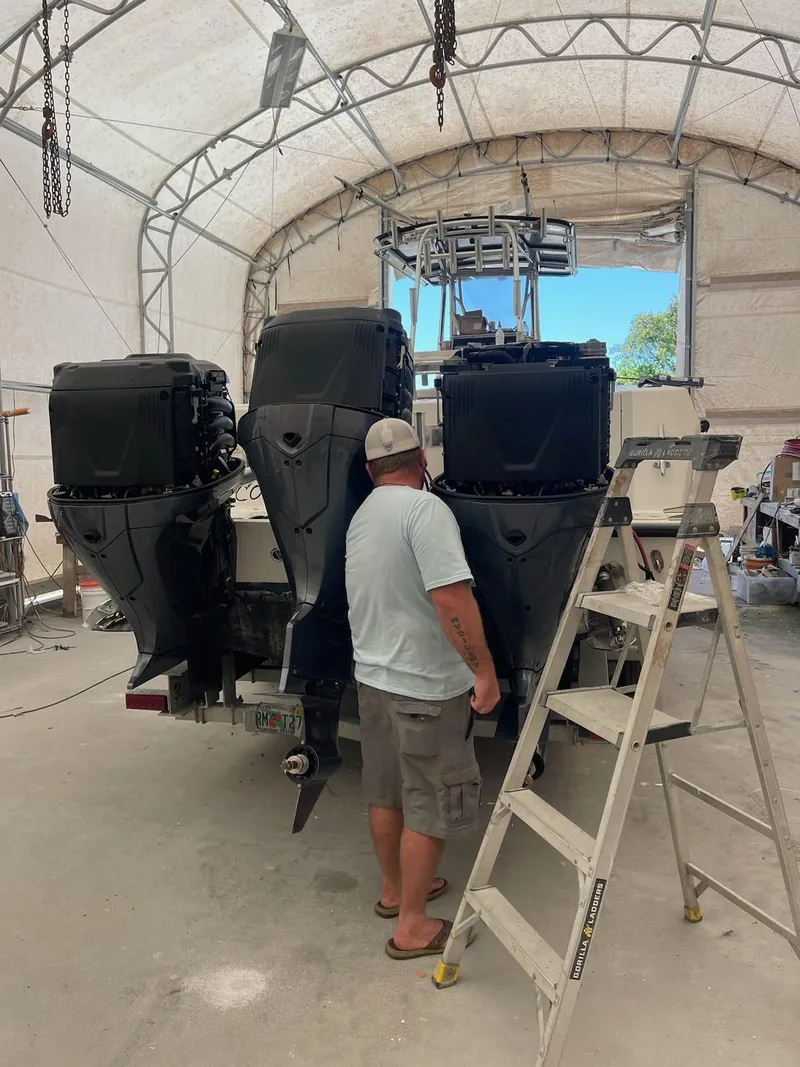 Slide: The Image of Man working on a 2000 Contender 36 Open boat with triple outboard engines. - 3