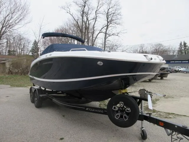 Slide: The Image of 2024 Four Winns HD3 boat on a trailer, parked outdoors. - 2