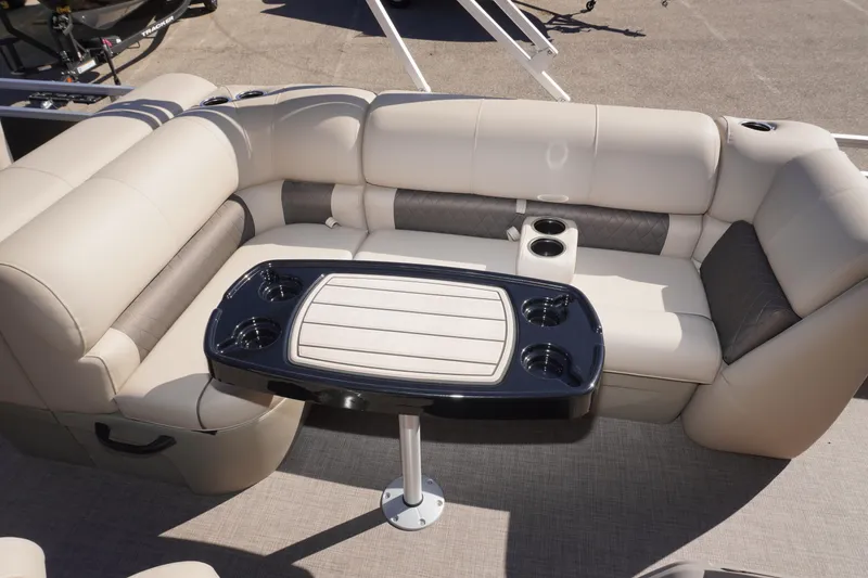 Slide: The Image of 2024 Sun Tracker Fishin' Barge 20 DLX interior with beige seating and table. - 11