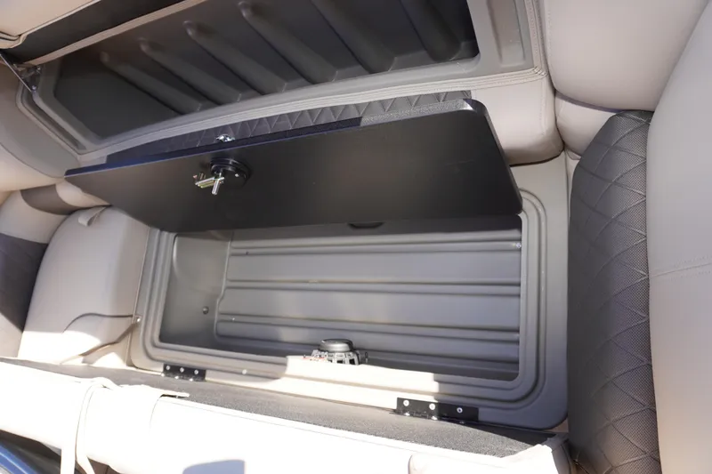 Slide: The Image of 2024 Sun Tracker Fishin' Barge 20 DLX storage compartment with open lid, showcasing interior space. - 12