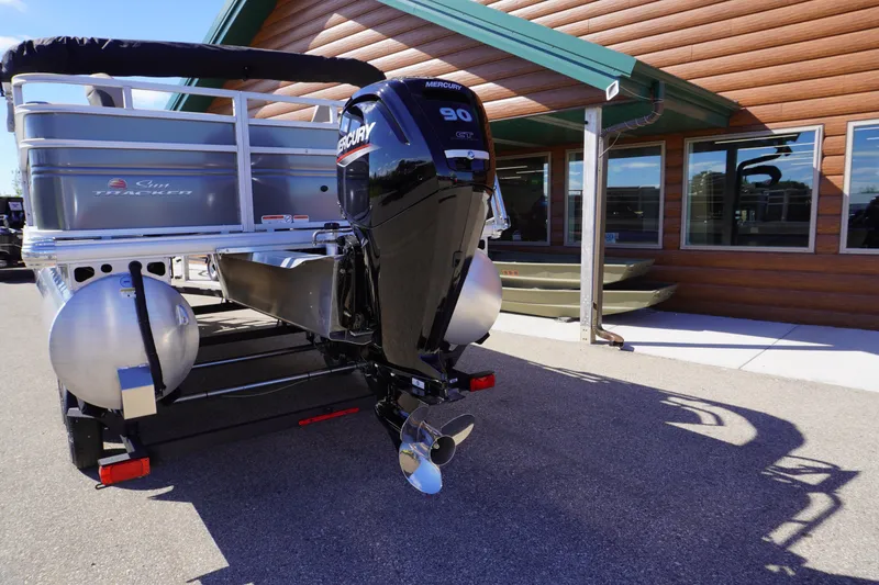 Slide: The Image of 2024 Sun Tracker Fishin' Barge 20 DLX with Mercury 90 engine, parked outside a building. - 21