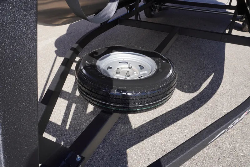 Slide: The Image of 2024 Sun Tracker Fishin' Barge 20 DLX trailer with spare tire mounted underneath. - 24