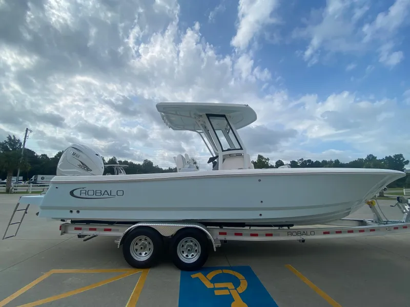 Slide: The Image of 2024 Robalo 266 Cayman boat on a trailer under a cloudy sky. - 2