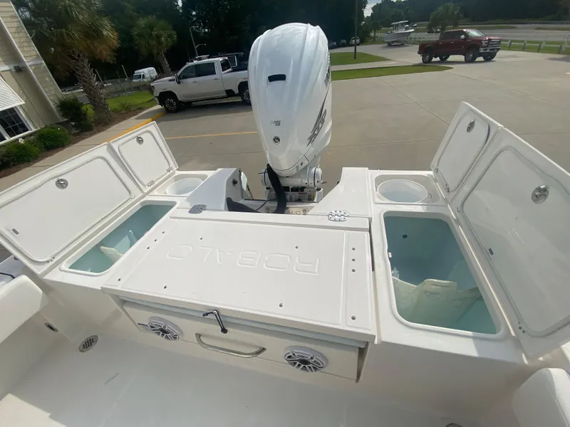 Slide: The Image of 2024 Robalo 266 Cayman boat with open storage compartments and outboard motor. - 7