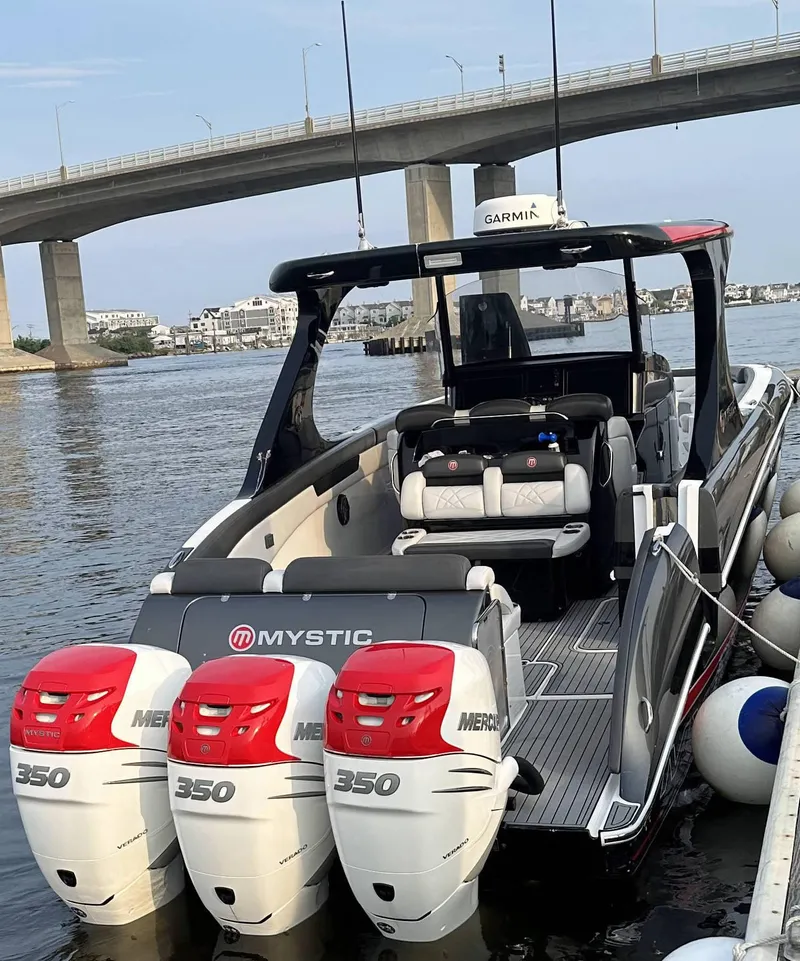 Slide: The Image of 2017 Mystic Powerboats M4200 with triple Mercury 350 engines docked near a bridge. - 4