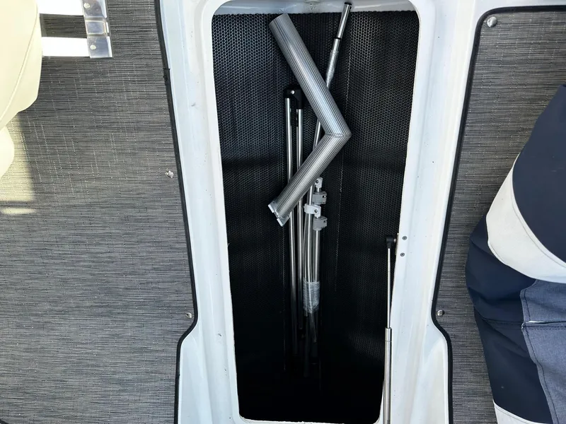Slide: The Image of 2023 Four Winns H2 boat storage compartment with metal poles and accessories. - 13